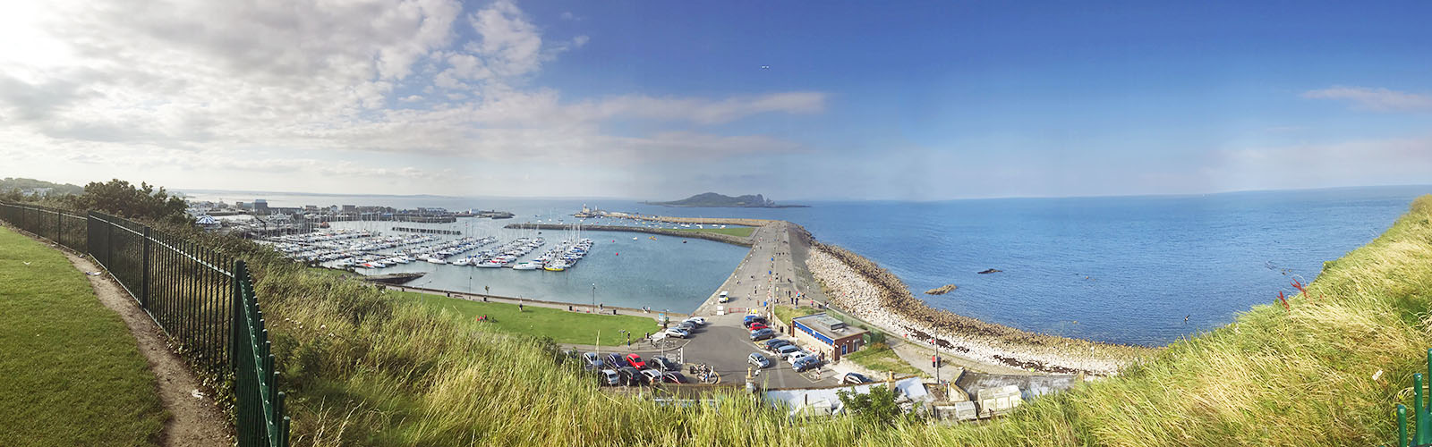 Taken from on top of a grassy hill, overlooking a marina filled with sailboats. 